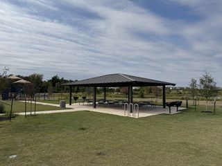 Community Amenities A scenic community pavilion in Horizon Lake by Taylor Morrison (Leander, TX), featuring shaded picnic tables, BBQ grills, and open green space.
