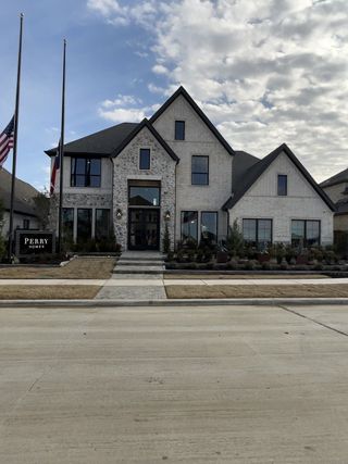 A beautiful stone and brick home with a well-manicured lawn in North Sky 55' by Perry Homes (Celina, TX).