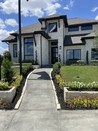 Street view A beautiful stone facade home with lush landscaping in Corley Farms 50' by Perry Homes, Boerne, TX.