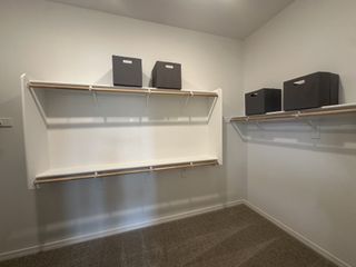 A spacious walk-in closet featuring shelving units with stylish storage bins and plush carpeting.
