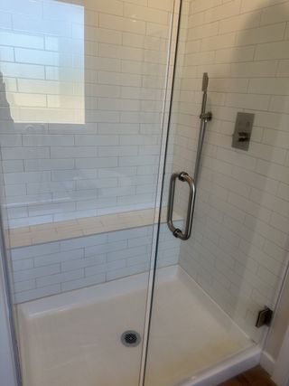 A sleek shower with white subway tiles and a built-in bench, enclosed by glass for a modern touch.