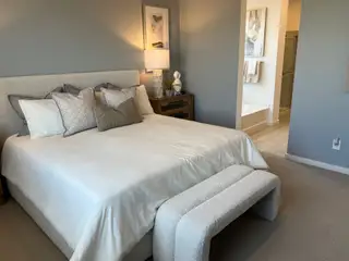 A cozy bedroom featuring a plush bed, soft lighting, and elegant decor, seamlessly connected to an en-suite bathroom.
