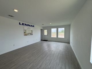 A spacious room with light wood flooring, large windows, and a modern minimalist design.