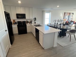 A modern kitchen with sleek black appliances, white cabinetry, and an open-concept dining area with contemporary decor.