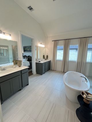 A spacious bathroom with dual vanities, a freestanding tub, elegant lighting, and large windows for natural light.