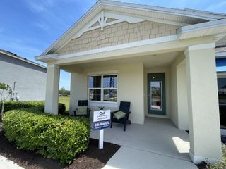 Street view A charming front porch with a welcoming entrance, lush landscaping, and cozy seating in Timberwalk by D.R. Horton (Mount Dora, FL).