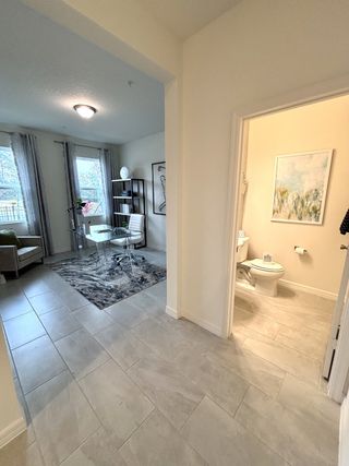 A modern home office with large windows, a sleek desk, and a cozy adjoining bathroom, featuring elegant tile flooring.