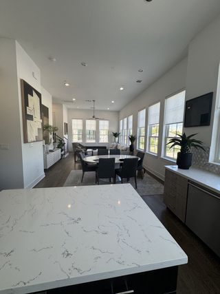 Model Home A modern dining area with a marble island, elegant dark chairs, and abundant natural light from large windows.
