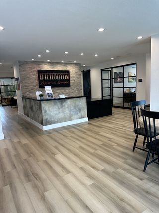 Model Home A modern office space with sleek wood flooring, a stylish reception desk, and elegant glass doors.