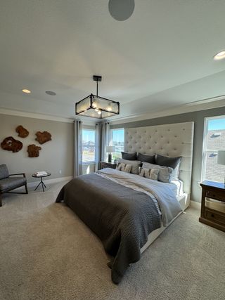 A chic bedroom with a tufted headboard, modern lighting, and neutral-toned decor creating a serene ambiance.