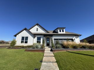 A modern white home with clean lines and lush landscaping in Sunfield by David Weekley Homes (Buda, TX).