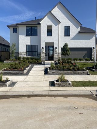 A modern white brick home with elegant landscaping in Brookewater by Westin Homes (Rosenberg, TX).