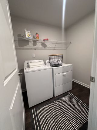 Model Home A modern laundry room with sleek appliances, dark flooring, and a striped rug, creating a functional and stylish space.