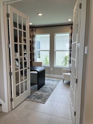 A cozy office space with French doors, large windows, and modern furnishings, creating a bright and inviting atmosphere.