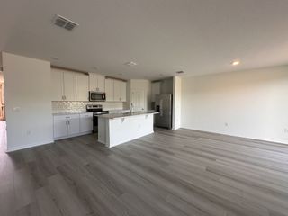 Spacious modern kitchen with sleek white cabinets, stainless steel appliances, and elegant wood flooring.