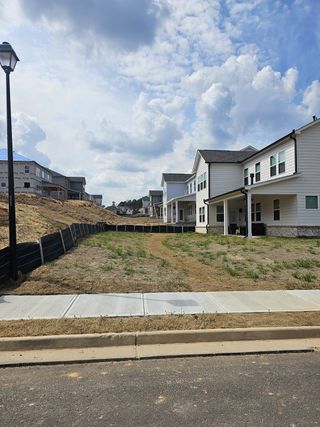 A newly developed neighborhood features modern homes with white siding and dark trim, situated along a paved street with sidewalks, in Bailey Fence by Taylor Morrison (Dacula, GA).