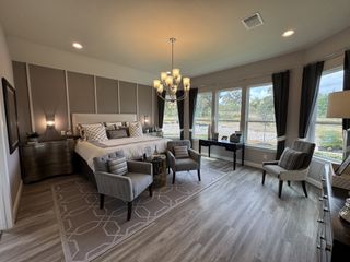 A spacious bedroom with a plush bed, elegant chandelier, and large windows offering serene garden views.