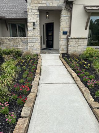 A charming stone exterior with lush landscaping in Stewart’s Forest by Sitterle Homes (Conroe, TX).