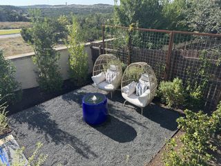A stylish covered patio with comfortable outdoor seating, overlooking a scenic backyard.