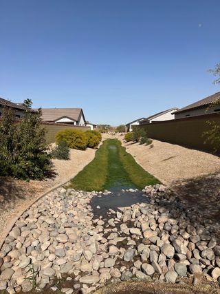 A serene landscaped pathway with rocks and greenery in West Santa Rosa Springs by K. Hovnanian® Homes (Maricopa, AZ).