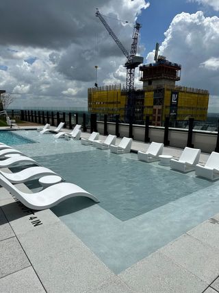 Luxurious rooftop pool with sleek loungers against a cityscape backdrop in Vesper by Pearlstone Partners (Austin, TX).