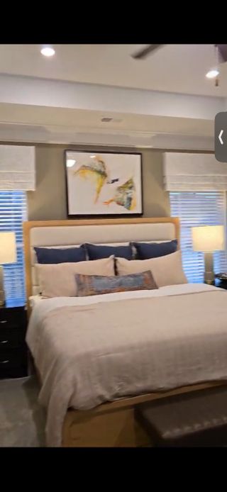 A cozy bedroom featuring a plush bed, elegant lamps, and tasteful abstract art.