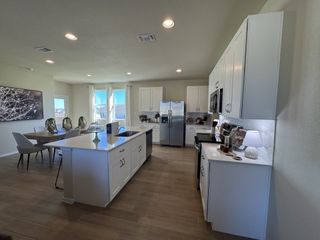 A contemporary kitchen with sleek white cabinetry, modern appliances, and an island adjacent to an inviting dining space.
