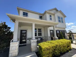 Charming two-story home with stone and siding facade in The Hills at Avery Centre by Century Communities (Round Rock, TX).