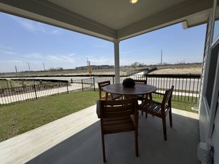 Model Home A cozy patio with a wooden table set and a scenic view of open land, perfect for relaxation and outdoor dining.