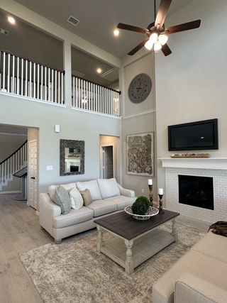 A spacious living room with high ceilings, a cozy fireplace, elegant decor, and plush beige sofas.