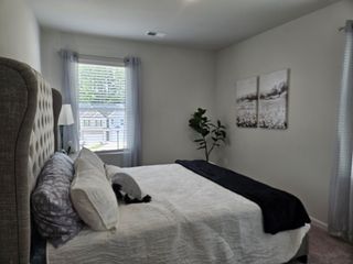 A cozy bedroom featuring a tufted headboard, soft lighting, and decor enhancing a tranquil atmosphere.