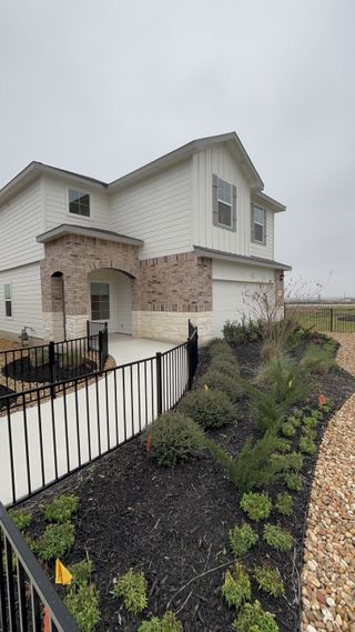 This two-story brick home with a well-maintained yard and modern features is located in the Avenida community by D.R. Horton (Converse, TX).