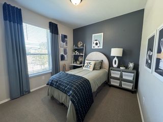 Model Home A cozy bedroom with a sporty theme, featuring a navy accent wall, stylish bedding, and modern decor elements.