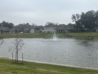 A picturesque pond with a fountain and stylish homes in Champions Oak by Long Lake Ltd. (Houston, TX).
