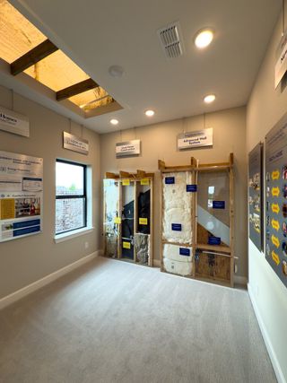A modern room showcasing construction techniques with exposed wall systems and informative displays.