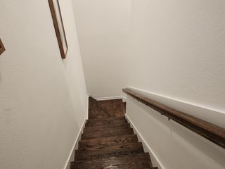 A wooden staircase with a sleek handrail and soft lighting descending to a lower level.