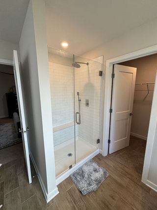 A modern bathroom showcasing a sleek glass shower, white subway tiles, and stylish wood-look flooring.