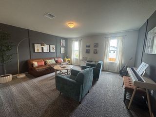 A cozy living room with a leather sofa, teal chairs, dark accent wall, and musical decor featuring a guitar and keyboard.