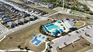 Community Amenities An aerial view of Crosswinds by Pulte Homes in Kyle, TX, showcasing its well-planned neighborhood, winding streets, and stunning community amenities.