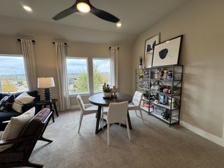 A cozy living area with a sleek ceiling fan, natural light, modern decor, and a round dining table.