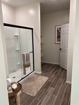 A modern bathroom featuring a spacious shower, wooden tiles, and sleek decor with subtle earth tones.