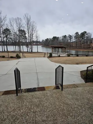 A serene lakefront view with a walking path and pavilion in Cresswind Georgia at Twin Lakes by Kolter Homes (Hoschton, GA).