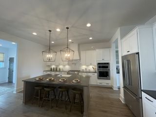 A modern kitchen with a large island, sleek countertops, white cabinetry, and stylish pendant lighting.