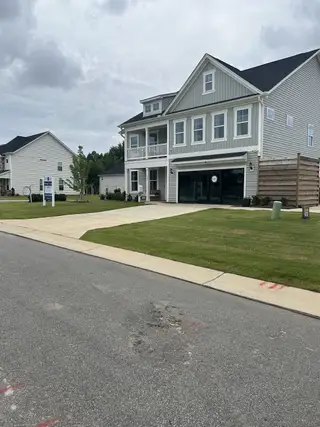 Street view A modern gray two-story home with a charming balcony in Cornwallis Landing by Mungo Homes (Garner, NC).