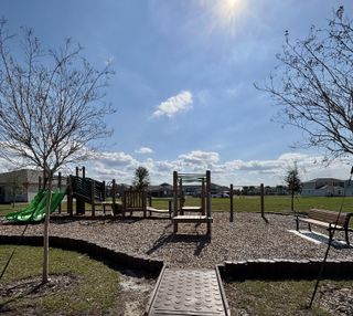 A scenic community playground with slides, climbing structures, and open green space in Meadowlark Landing by Mattamy Homes (Apopka, FL).