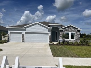 A modern stone-accented home with a spacious driveway in Avalon Woods by D.R. Horton (Newberry, FL).