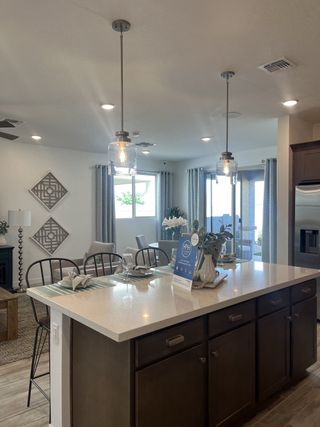 Modern kitchen with sleek pendant lights, spacious island, and dining area. Bright and inviting with contemporary decor.
