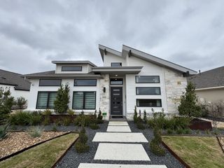 Model Home A stunning modern exterior with sleek architecture, stone accents, and lush landscaping in Vista Alta Del Veramendi by Perry Homes (New Braunfels, TX).