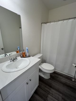 A modern bathroom with a sleek white vanity, spacious mirror, and dark-toned flooring.