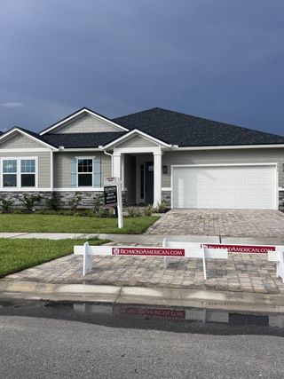 A modern gray home with stone accents and a paved driveway in TrailMark by Richmond American Homes (St. Augustine, FL).